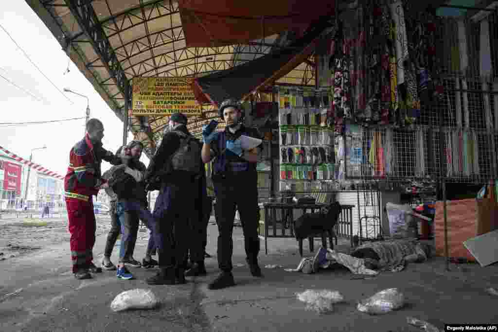 Bystanders try to console Sabina (second from left) as she is kept away from the lifeless body of her husband, Artem Pohorelets, who was killed by Russian shelling at the Barabashovo market on July 21.