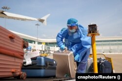 Работник аэропорта в Ухане загружает багаж. 14 июля 2022 года