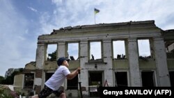 Kisfiú rollerezik a városháza lerombolt épülete előtt Ohtirkában 2022. augusztus 1-jén