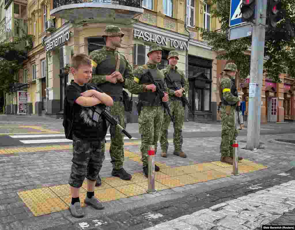 Egy kisfiú játék puskával és szigorú tekintettel ukrán katonák társaságában Kijev központjában június 22-én