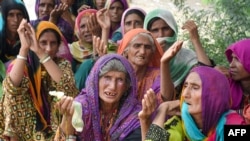 Women wait for relief aid near their damaged houses in the flood-affected town of Gandawah in the southwestern province of Balochistan on August 2. 