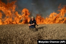 Jevgenyij Maloletka újságíró rohan a lángok elől egy égő búzamezőn Harkiv régióban, az orosz határ közelében 2022. július 29-én
