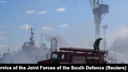 Zjarrfikësit ukrainas punojnë në vendin e një sulmi me raketa ruse në portin e Odesës më 23 korrik.
