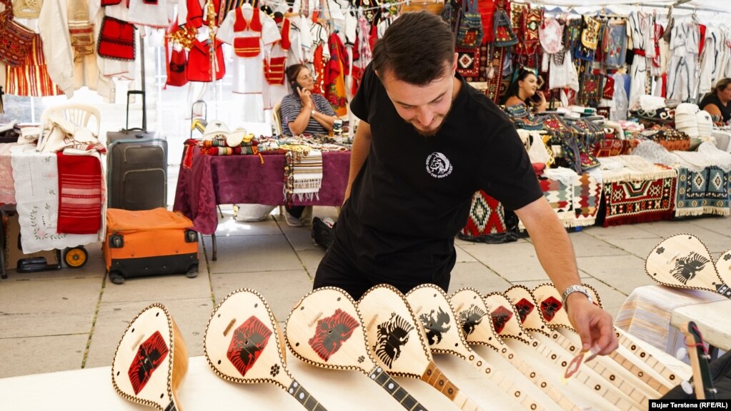 Një vizitor duke shikuar çiftelitë e zbukuruara me motive kombëtare. 