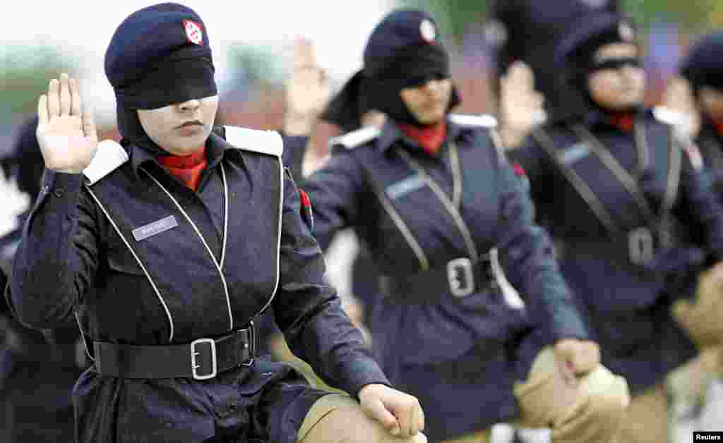 Pakistani police-academy graduates signal the completion of their weapon disassembly and assembly while being blindfolded, during their graduation ceremony in Islamabad. (Reuters/Caren Firouz)