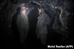 Miners with headlamps stand inside an emerald mine shaft.