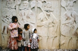 ბავშვები ქვაზე ამოკვეთილი გამოსახულების წინ შირაზში, სამხრეთ ირანში.