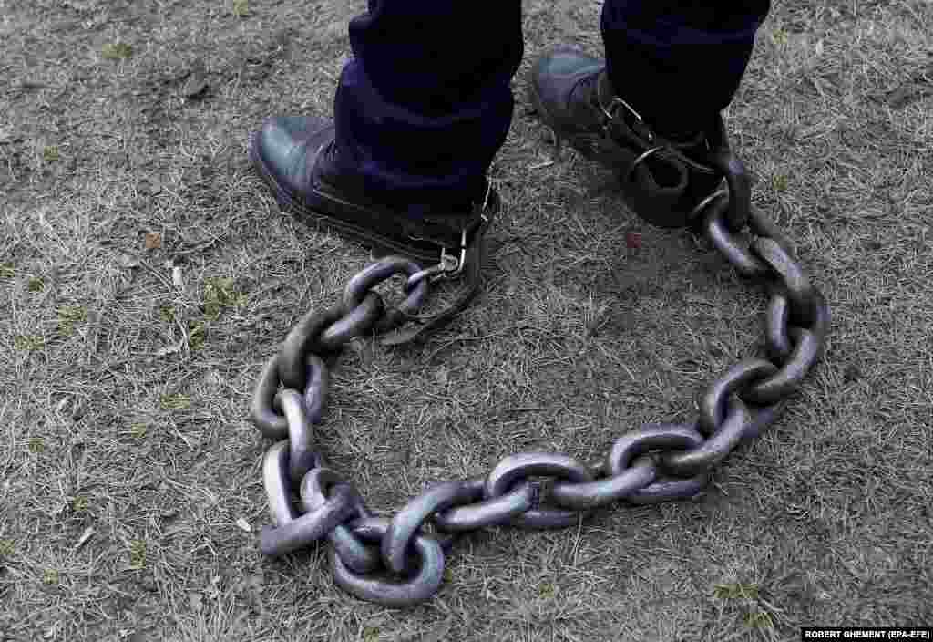 A Romanian policeman has his legs bound with a heavy chain during a rally held in front of the Romanian parliament in Bucharest. About 1,500 police officers, prison guards, and retired defense system employees from all over the country joined a protest demanding that the government comply with the law on the remuneration of staff paid from public funds.