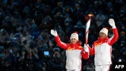 На церемонии открытия Игр в Пекине 4 февраля честь зажечь олимпийский огонь Китай предоставил уйгурской спортсменке Динигер Йиламуцзян (слева) и лыжнику-ханьцу Чжао Цзявэню