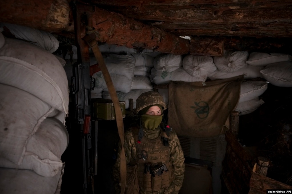 Një ushtare ukrainase qëndron në një llogore. 