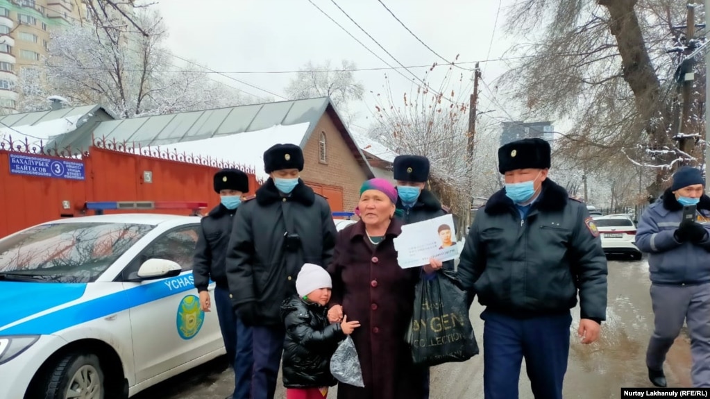 Участница пикета с ребенком в сопровождении задержавших ее полицейских недалеко от консульства Китая. Алматы, 8 февраля 2022 года