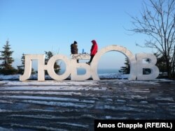 Two young Mariupol locals enjoy a makeshift picnic on a sign saying “Love” in the Ukrainian language on February 6.