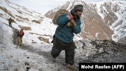 Miners carry bags of ore to search for emeralds near a mine in Afghanistan's northern Panjshir Province.