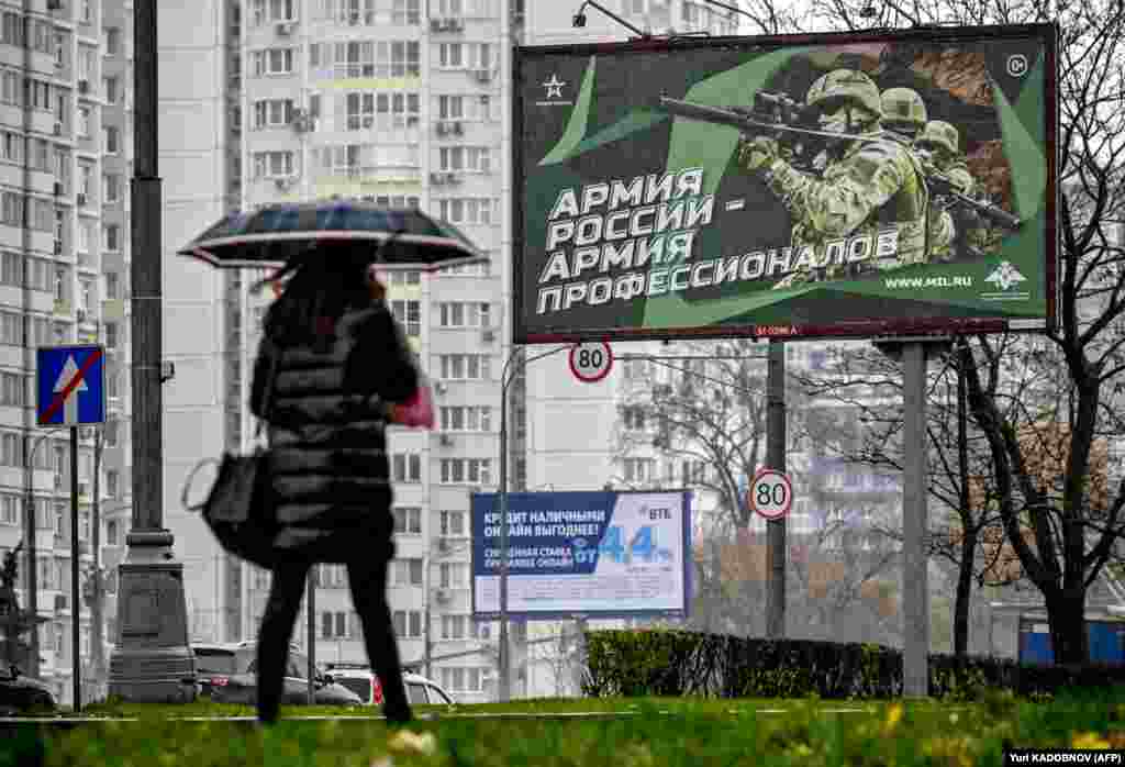 A pedestrian walks past a poster displaying Russian soldiers with a slogan reading &quot;Army of Russia -- Army of Professionals&quot; on a street in Moscow.