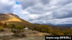 Вид на Богатое ущелье с западной стороны, с берега озера, которое значится как обычный водоем. Слева над селом нависает гора Коба-Кая (Пещера)