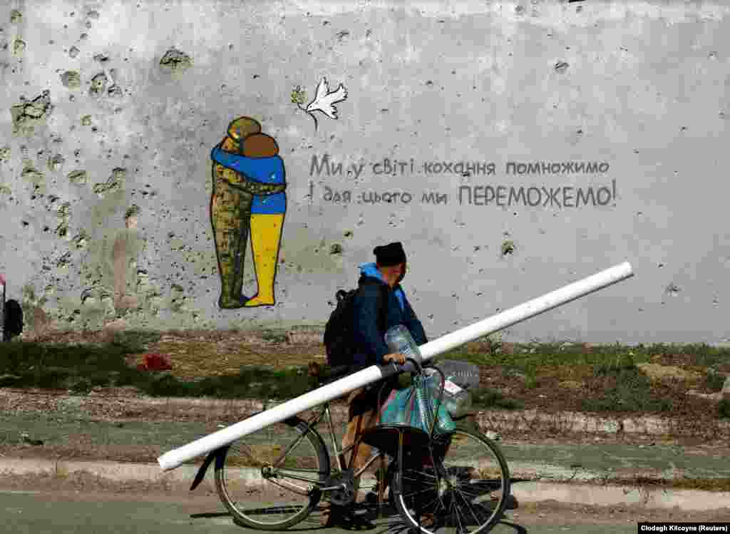 Një pikturë e fotografuar më 18 tetor në një mur të dëmtuar nga beteja në Kupjansk, një qytet në verilindje të Ukrainës, i rimarrë së fundmi nga forcat ukrainase. Teksti thotë &quot;Do ta shumëfishojmë dashurinë në botë dhe për këtë do të fitojmë!&quot; &nbsp;