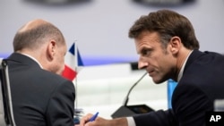 Președintele francez Emmanuel Macron vorbește cu cancelarul german Olaf Scholz la începutul celei de-a doua sesiuni plenare a summitului NATO de la Madrid, 29 iunie 2022