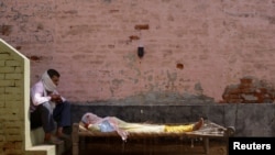  Мъж седи до жена си, която страда от висока температура по време на пандемията от COVID-19, Индия, 2021 година Фотограф: Аднан Абиди 