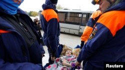 Pripadnici ruskog Ministarstva za vanredne situacije nose ženu koja je evakuisana iz Hersona pod ruskom kontrolom, u gradu Oleški u Hersonskoj oblasti, područje Ukrajine pod kontrolom Kremlja, 22. oktobar 2022.