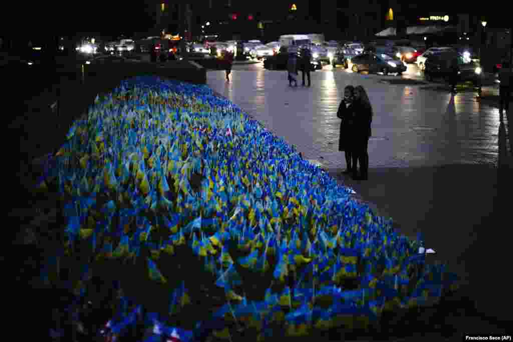 Women stand next to Ukrainian flags placed in memory of civilians killed during the war on central Kyiv&#39;s Independence Square on October 20. &nbsp;