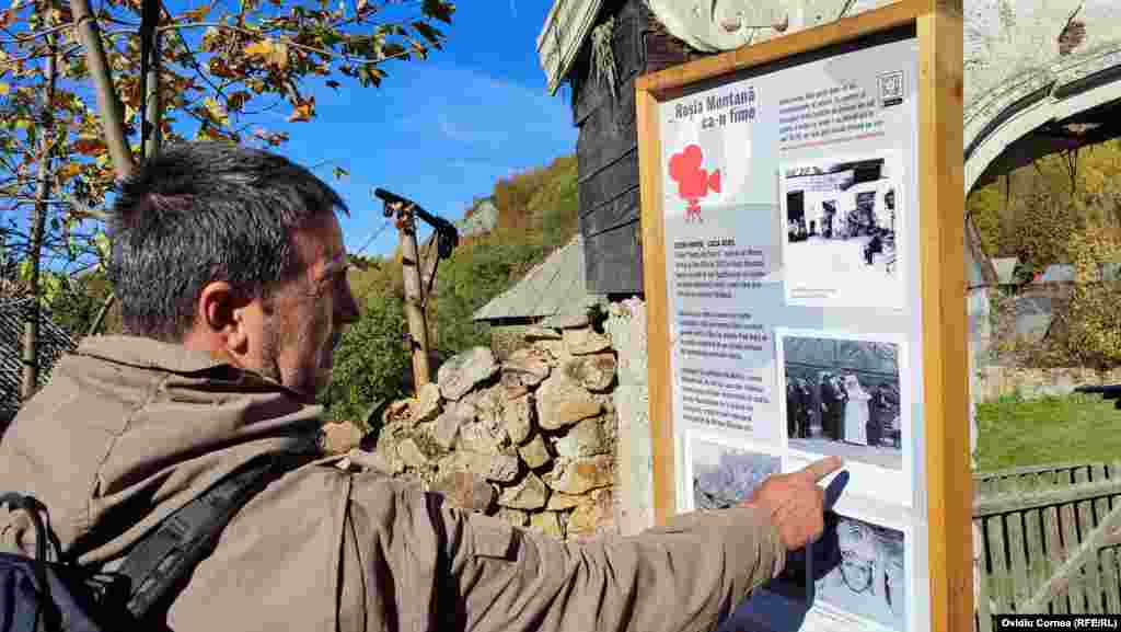 Călin Caproș, unul din cei mai buni cunoscători ai Roșiei Montane, indică o scenă din filmul Nunta de Piatră filmat în Roșia Montană, pe o pancartă amplasată în fața casei unde a fost filmată scena nunții.