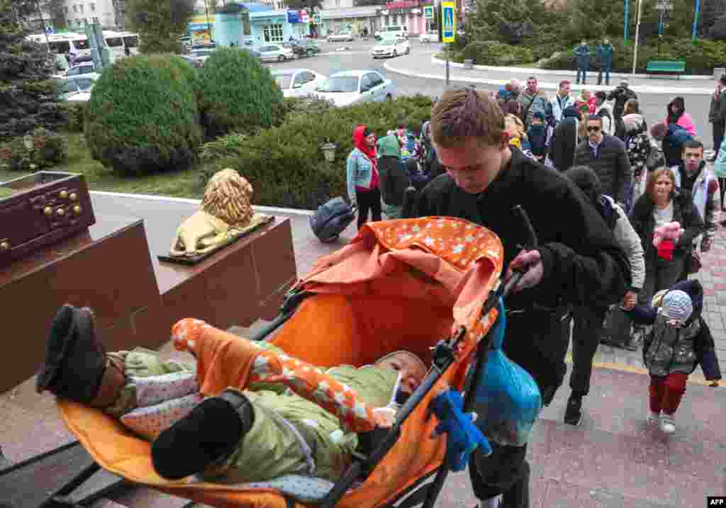 Мужчина несет ребенка в коляске вверх по лестнице Джанкойского железнодорожного вокзала в Крыму 21 октября. По данным российского информационного агентства &laquo;Интерфакс&raquo;, с 18 октября регион покинули около 25 тыс. человек.