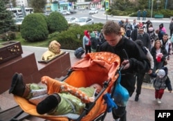 Мужчина несет ребенка в коляске вверх по лестнице Джанкойского железнодорожного вокзала в Крыму 21 октября. По данным российского информационного агентства «Интерфакс», с 18 октября Херсонскую область покинули около 25 тыс. человек.