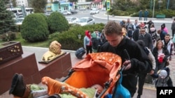 Мужчина везет ребенка в коляске вверх по лестнице Джанкойского железнодорожного вокзала в Крыму, 21 октября. По данным российского информационного агентства «Интерфакс», с 18 октября Херсонскую область покинули около 25 тыс. человек.