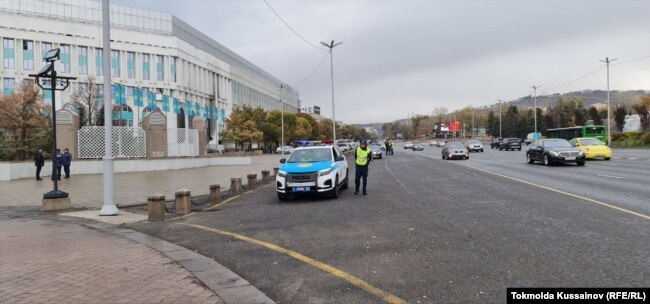 Полицейский автомобиль и сотрудники сил безопасности у монумента Независимости возле площади Республики. Алматы, 25 октября 2022 года