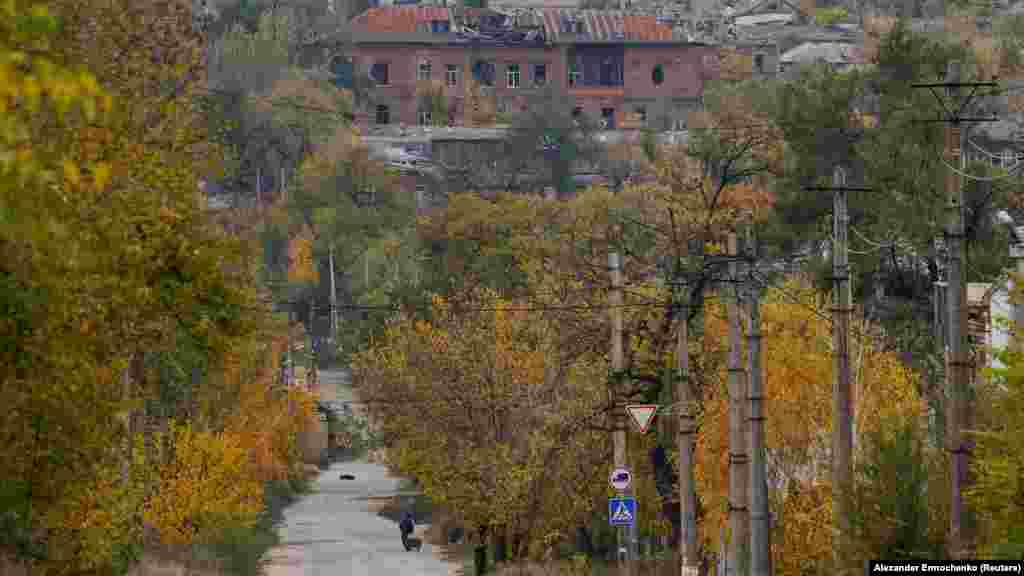 Një burrë duke shtyrë një karrocë drejt një periferie të shkatërruar të Mariupolit, më 29 tetor.