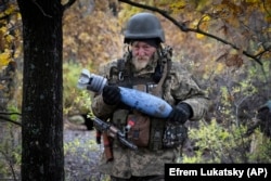 A Ukrainian soldier carries a shell with a written message to the Russian Army at a frontline position near Bakhmut on October 27.