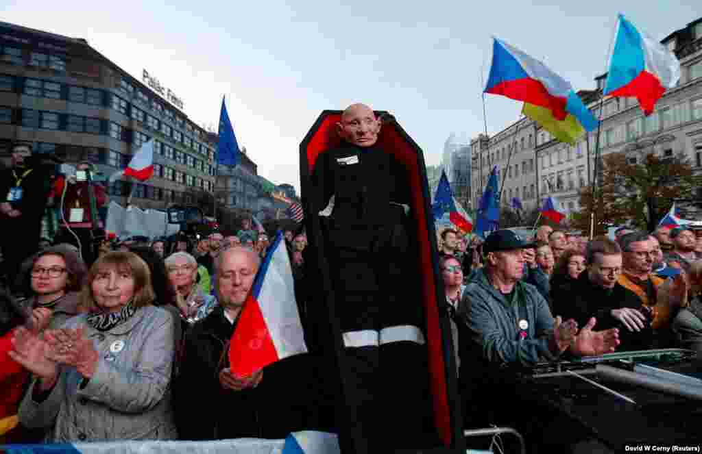 Manifestanți stau lângă o statuie care îl înfățișează pe președintele rus Vladimir Putin.