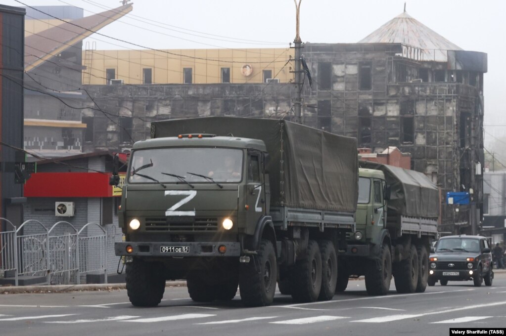Një foto e bërë më 19 tetor tregon kamionë ushtarakë rusë përpara një ndërtese të dëmtuar rëndë në qendër të Mariupolit.