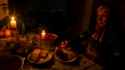 A woman eats dinner by candlelight during a blackout to conserve energy in the Moldovan capital, Chisinau. (file photo)