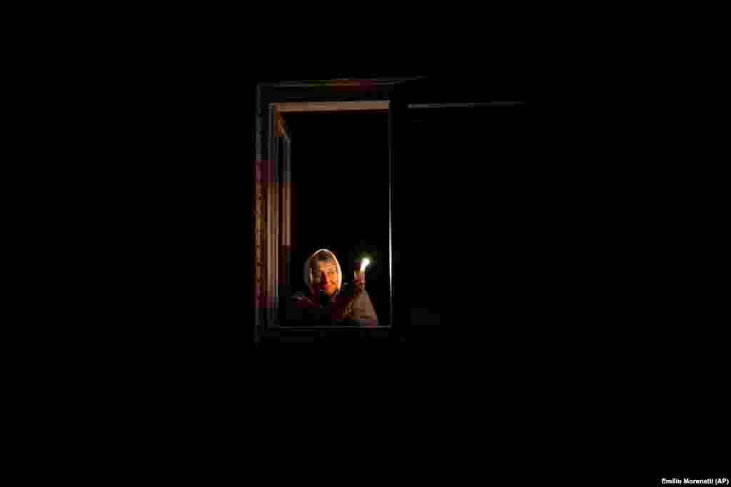 Kateryna, 70, looks out her window while holding a candle during a power outage in Borodyanka on October 20. Ukrainian President Volodymyr Zelenskiy warned EU leaders on October 20 that Russian attacks that have destroyed a large portion of Ukraine&#39;s energy infrastructure are aimed in part at provoking a new wave of migration of Ukrainians to EU countries. &nbsp;