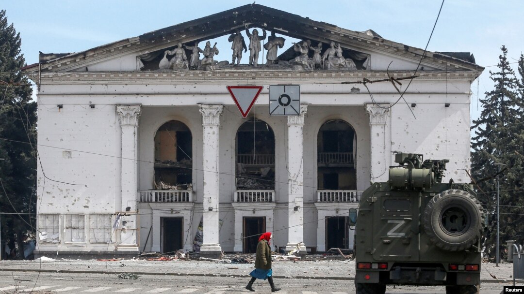A woman walks next to an armored vehicle manned by pro-Russian troops outside the desroyed Donetsk Academic Regional Drama Theater in Mariupol on April 10. 