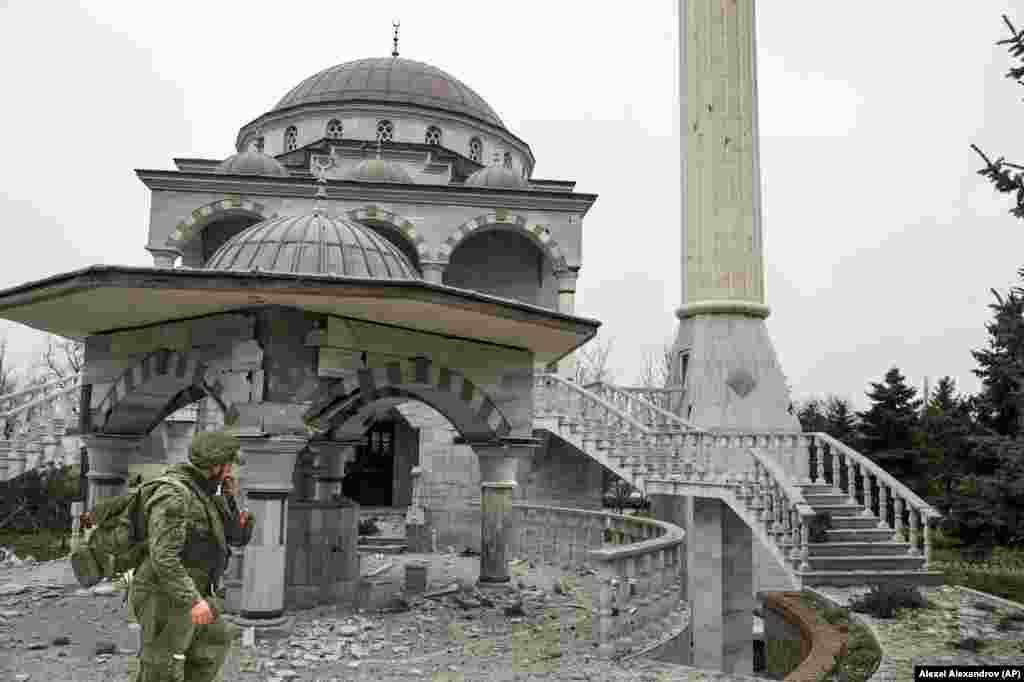 A pro-Russian militant walks past the battle-damaged mosque in April 2022.&nbsp;