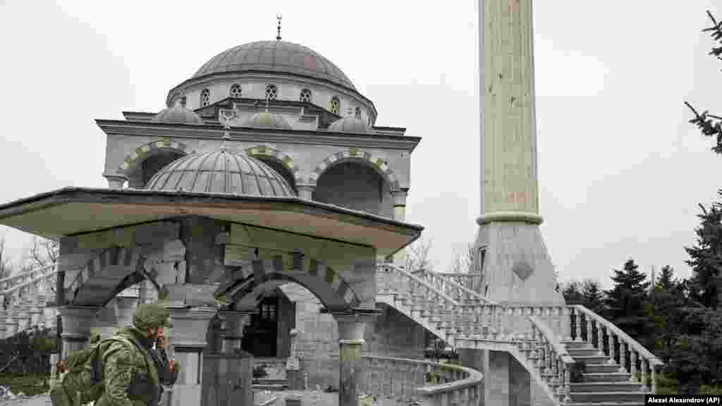 A pro-Russian militant walks past the battle-damaged mosque in April 2022.&nbsp;