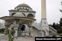 Проросійський бойовик проходить повз пошкоджену під час боїв мечеть у Маріуполі в квітні 2022 року