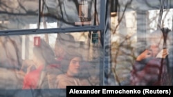 O fată se uită prin geamul unui autobuz în timp ce civili din Mariupol, inclusiv cei evacuați de la oțelul Azovstal, călătoresc într-un convoi către Zaporojie, în timpul conflictului dintre Ucraina și Rusia din regiunea Donețk, Ucraina, 2 mai 2022. REUTERS/Alexander Ermochenko