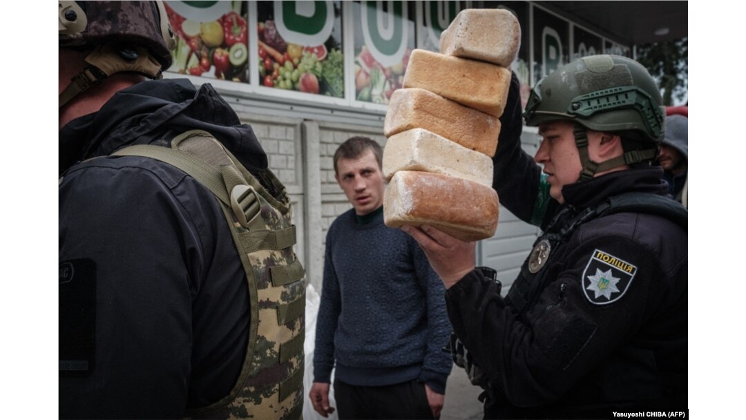 Imagine de arhivă cu câțiva polițiști ucraineni care distribuie pâine locuitorilor din orașul Lîman, în estul Ucrainei, pe 2 mai 2022.