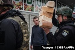 Imagine de arhivă cu câțiva polițiști ucraineni care distribuie pâine locuitorilor din orașul Lîman, în estul Ucrainei, pe 2 mai 2022.