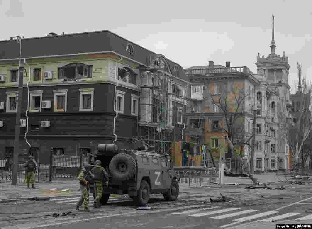 Russian troops unloading an armored vehicle near the Stalinist-era spire house in April 2022.&nbsp;