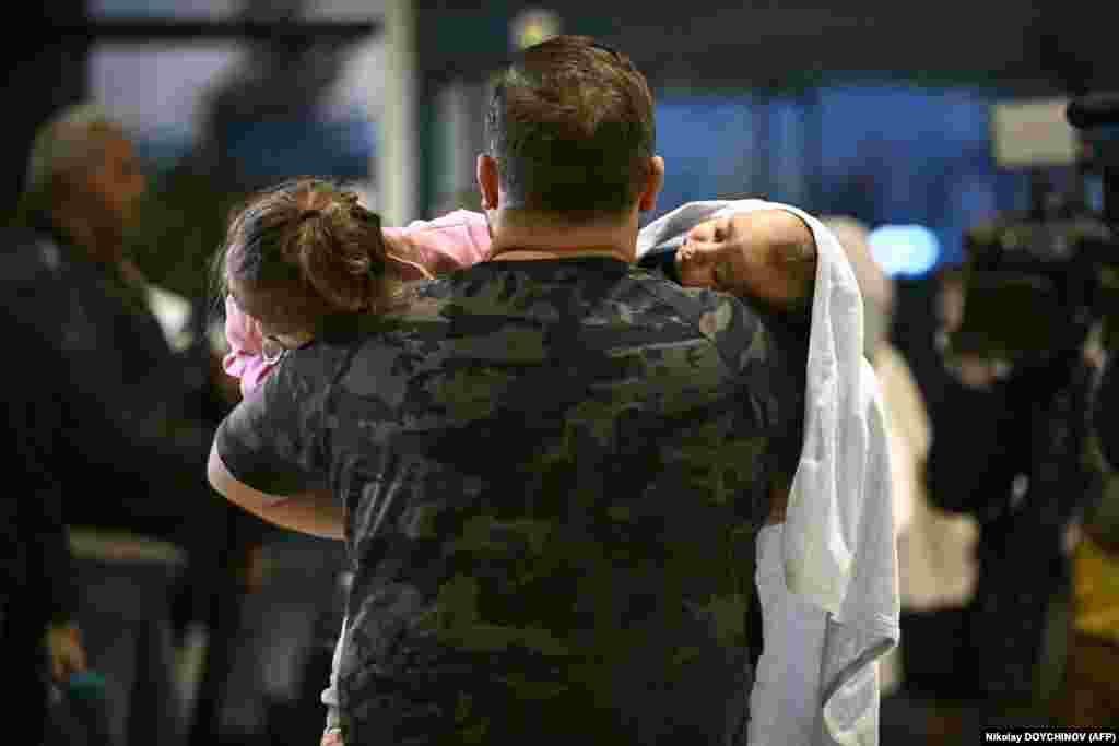 A man carries two children after arriving in Sofia airport on a Bulgarian government evacuation flight from Lebanon.&nbsp;