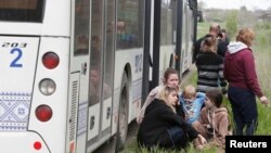 Люди отдыхают рядом с автобусом, пока мирные жители Мариуполя, в том числе эвакуированные с металлургического завода «Азовсталь», едут колонной в Запорожье во время украинско-российского конфликта в Донецкой области, Украина, 2 мая 2022 года. 