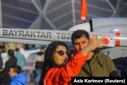 Visitors to the Teknofest Aerospace and Technology Festival in Baku pose with a Bayraktar drone on May 28.