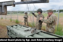 Egy HIMARS-rakétakapszulát helyeznek fel egy teherautóra a Wyomingi Nemzeti Gárda emberei egy gyakorlaton