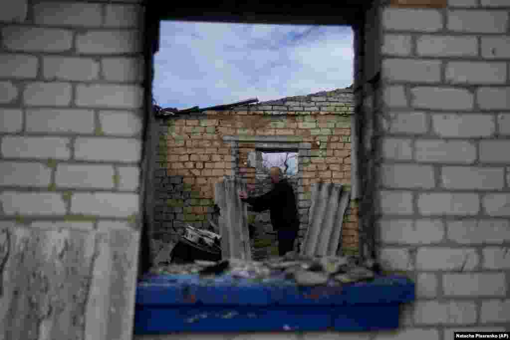 Eduard Zelenskiy looks for items that he can salvage in his destroyed home.