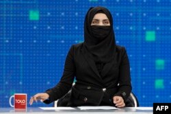 A female presenter for TOLOnews, Thamina Usmani, covers her face in a live broadcast at the TOLO TV station in Kabul.