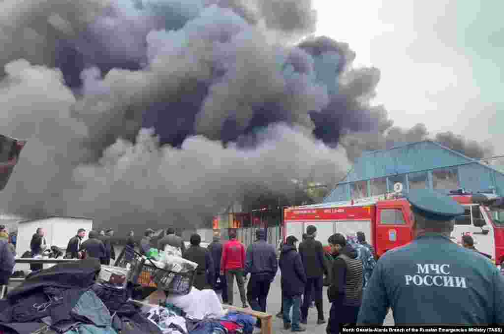 Местные жители наблюдают, как огонь охватывает рынок во Владикавказе, городе недалеко от границы с Грузией, 6 мая
